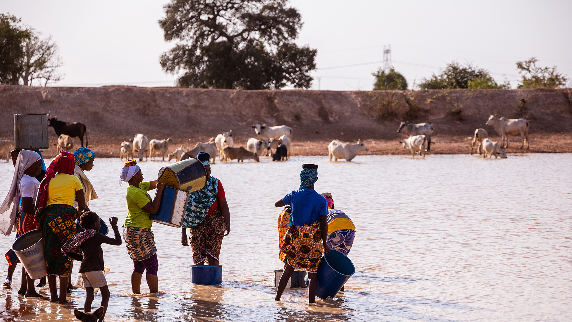 Some people drawing water from a river.
